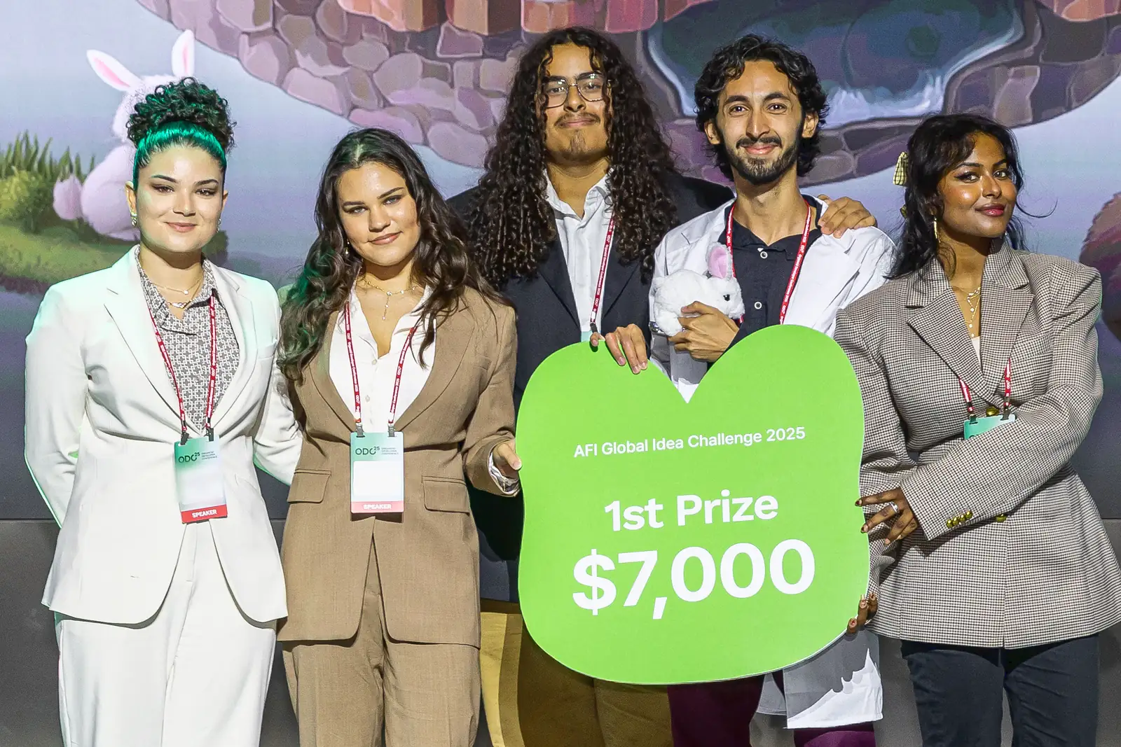The five SkipLab teammates on stage in Seoul holding the AFI Global Idea Challenge 2025 sign reading 1st Prize, $7,000. Mohammed, in a white lab coat, holds a small toy rabbit.